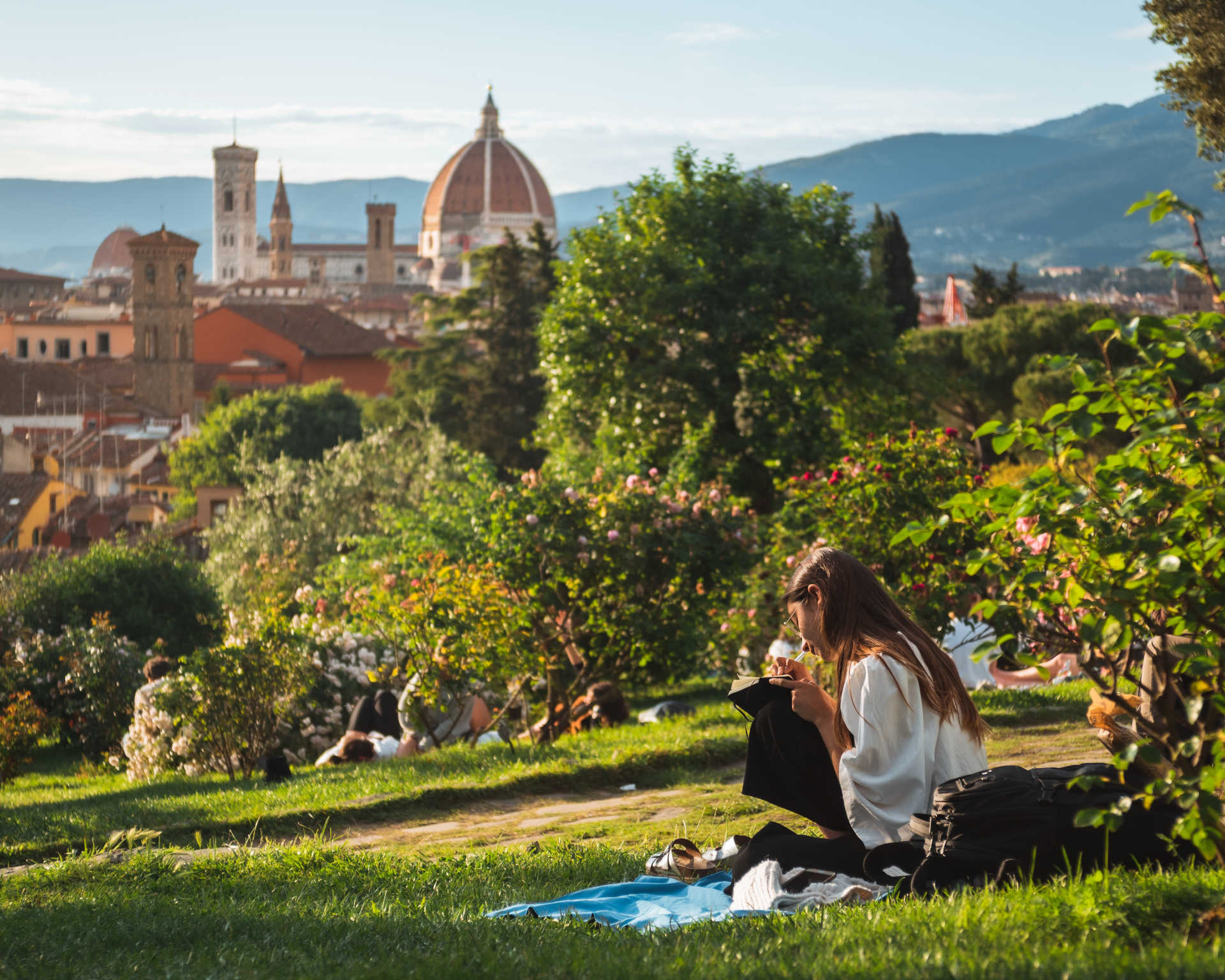Girl sitting on the grass with a beautiful view of Santa Maria del Fiore of Florence at the background